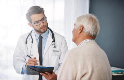 Male doctor with clipboard talks with mesothelioma patient